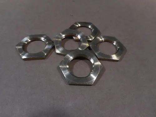 Fünf metallische Sechskantmuttern liegen auf einer grauen Oberfläche. Sie sind für den Einsatz in Verbindung mit Remeha-Produkten geeignet.